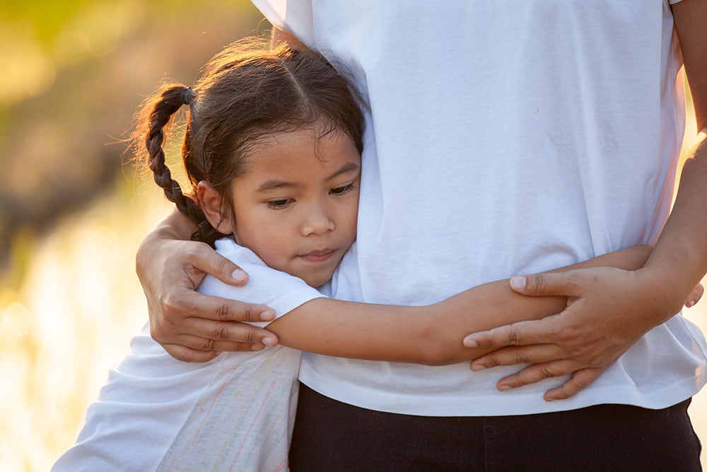 Sad asian child girl hugging her mother in the paddy field with the sunlight