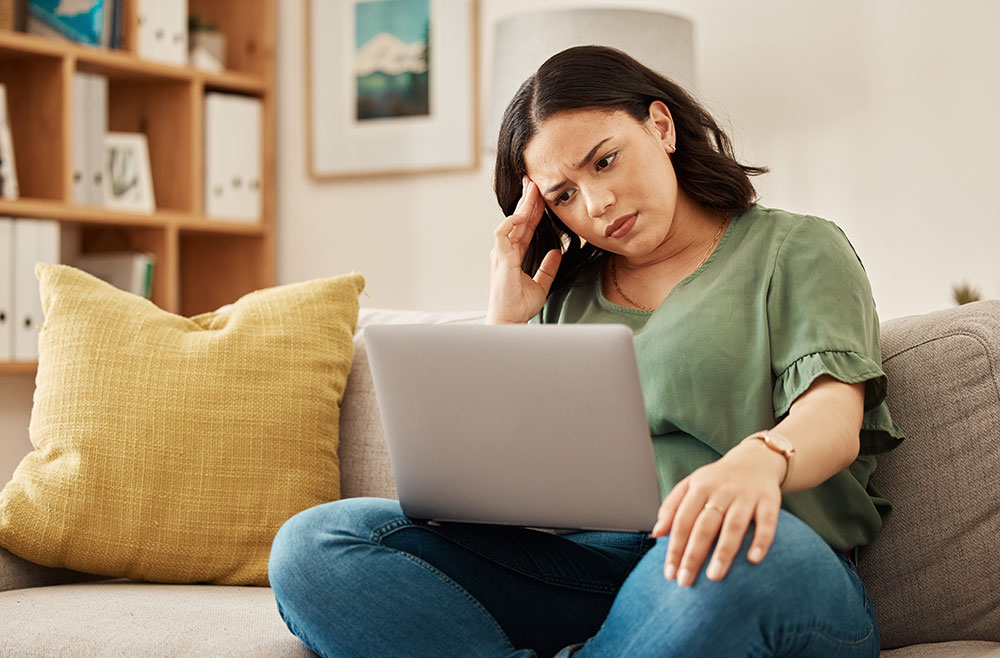 Remote work, stress and woman with laptop, headache and burnout on sofa, frustrated and annoyed at home. Freelance, glitch and lady online with anxiety from 404, internet or tax crisis in living room