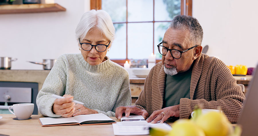 Senior couple, budget and finance notebook with writing
